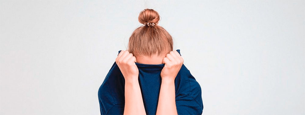 Девушка с симптомами панической атаки прячет голову в свитер